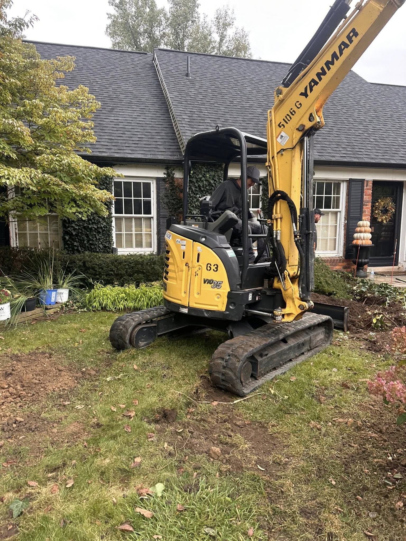 Mini excavator doing sewer line work in residential yard