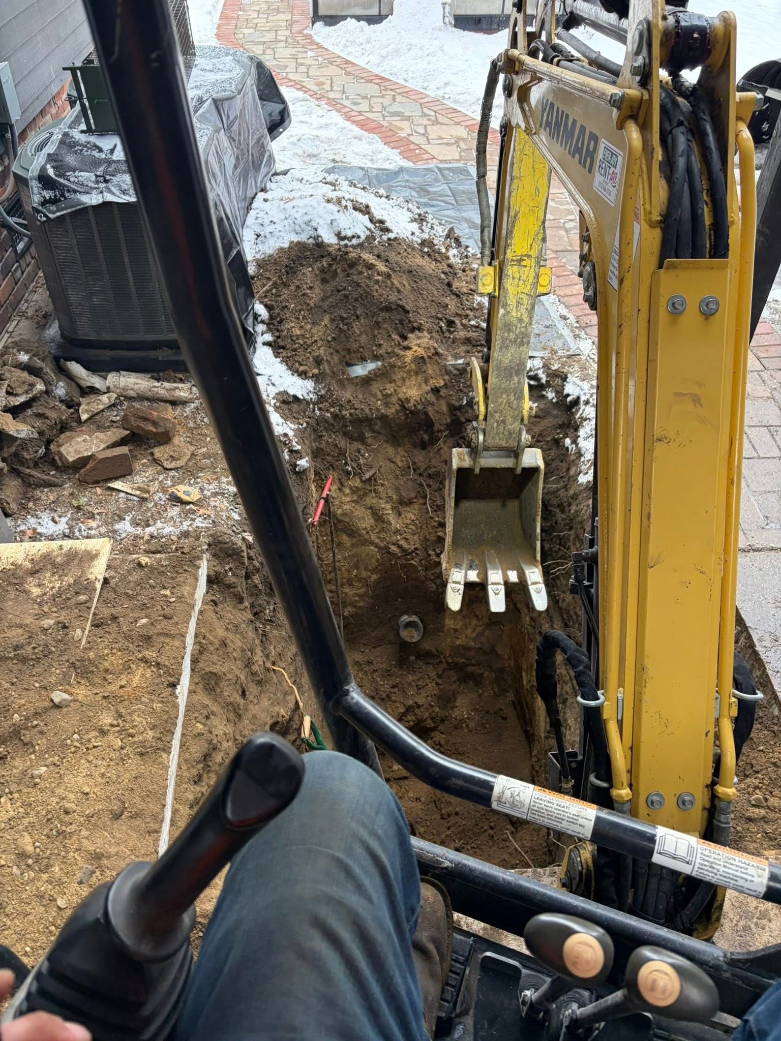 Mini excavator digging for sewer line at residential property